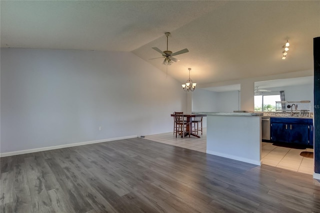 unfurnished living room featuring vaulted ceiling, a sink, ceiling fan with notable chandelier, and wood finished floors