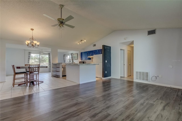 kitchen featuring ceiling fan with notable chandelier, white refrigerator, vaulted ceiling, blue cabinetry, and light hardwood / wood-style floors