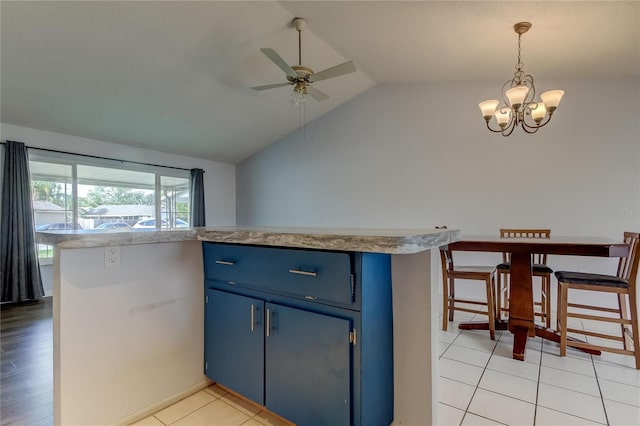 kitchen featuring ceiling fan with notable chandelier, blue cabinets, hanging light fixtures, vaulted ceiling, and light hardwood / wood-style floors