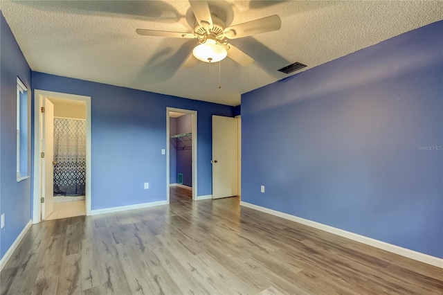 spare room with ceiling fan, a textured ceiling, and light wood-type flooring