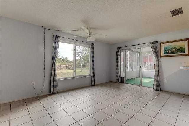 spare room featuring light tile patterned floors, ceiling fan, a textured ceiling, and visible vents