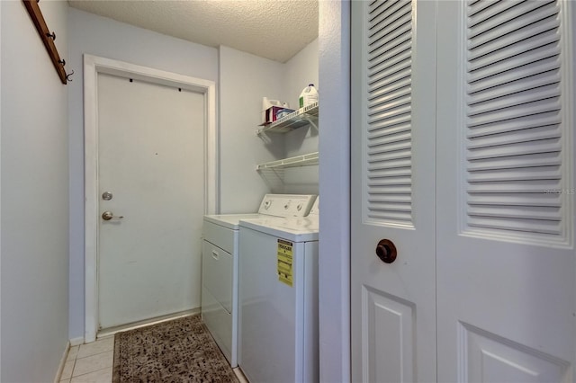 washroom with laundry area, light tile patterned floors, baseboards, washing machine and clothes dryer, and a textured ceiling