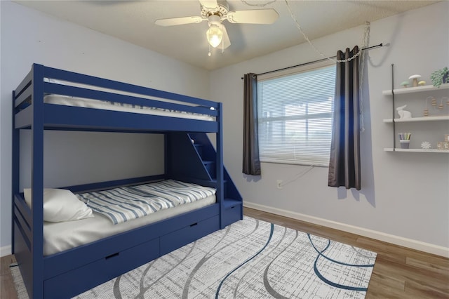 bedroom with dark wood finished floors, a ceiling fan, and baseboards