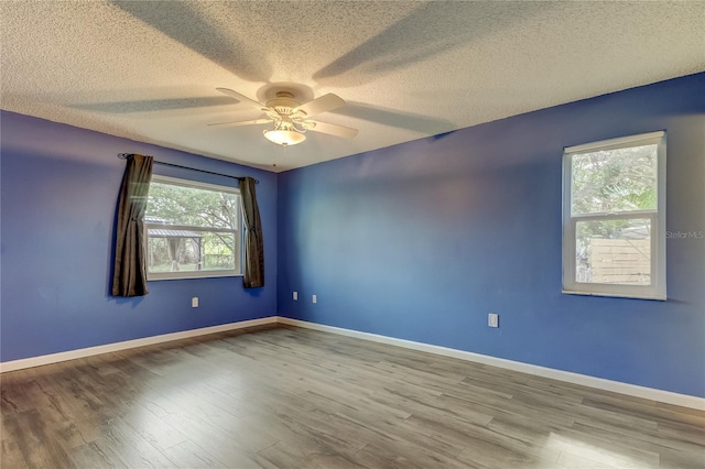 empty room featuring a textured ceiling, wood finished floors, a ceiling fan, and baseboards