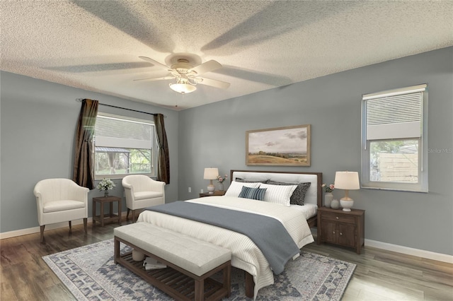 bedroom with multiple windows, baseboards, and wood finished floors