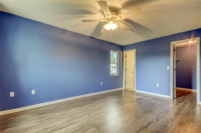 unfurnished room with a textured ceiling, wood finished floors, a ceiling fan, and baseboards