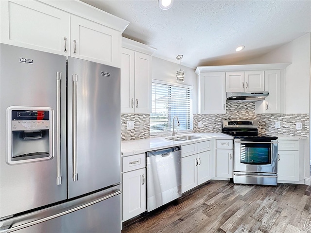 kitchen featuring sink, wood-type flooring, decorative light fixtures, white cabinets, and appliances with stainless steel finishes