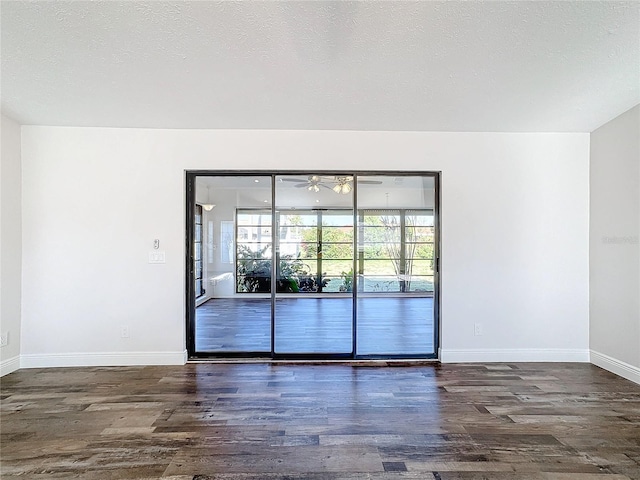 empty room with a textured ceiling and dark hardwood / wood-style floors