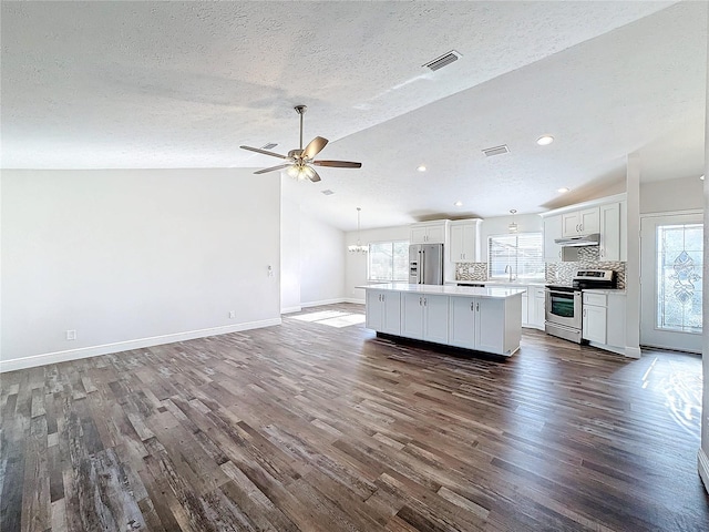 kitchen featuring dark hardwood / wood-style flooring, white cabinets, stainless steel appliances, and vaulted ceiling