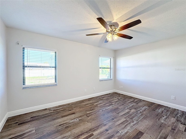 empty room featuring ceiling fan, dark wood-type flooring, a healthy amount of sunlight, and a textured ceiling