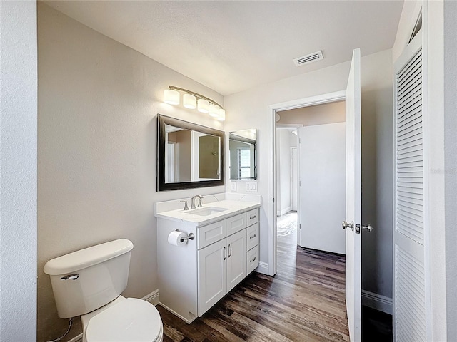 bathroom with wood finished floors, toilet, baseboards, and vanity