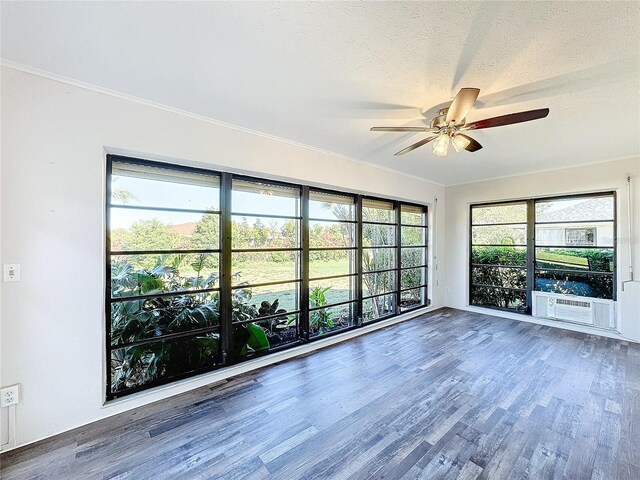 spare room featuring ceiling fan, wood finished floors, healthy amount of natural light, crown molding, and a textured ceiling
