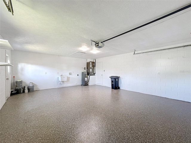 garage featuring water heater, sink, and a garage door opener