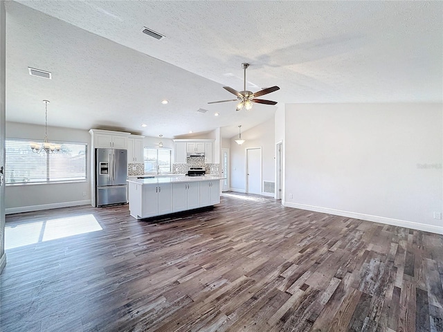 kitchen with stainless steel fridge, open floor plan, a textured ceiling, lofted ceiling, and baseboards