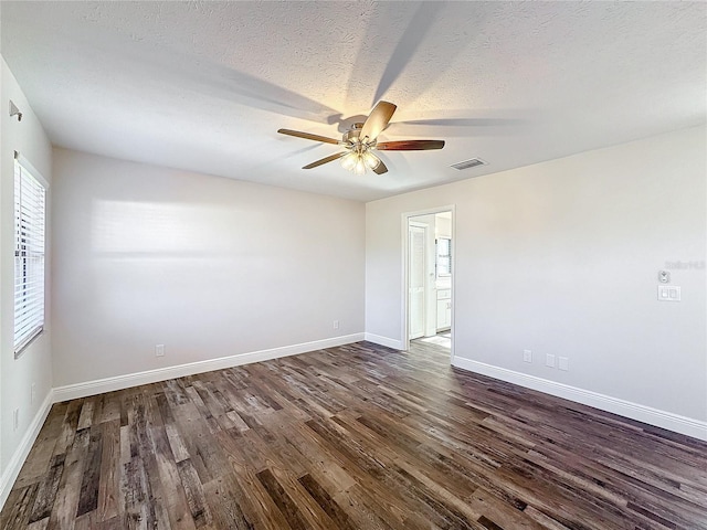 unfurnished room featuring dark wood finished floors, ceiling fan, baseboards, and a textured ceiling