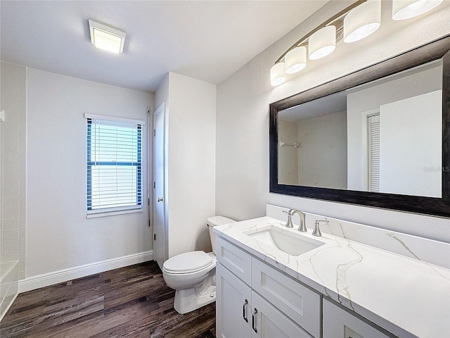 full bath featuring wood finished floors, toilet, vanity, baseboards, and a bathtub