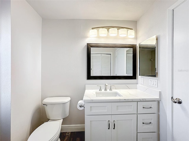 bathroom with baseboards, toilet, vanity, and wood finished floors