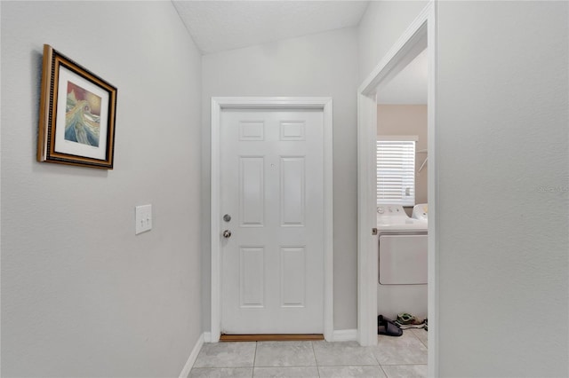 entryway featuring light tile patterned floors, a textured ceiling, separate washer and dryer, and lofted ceiling