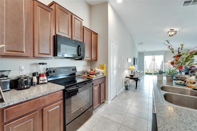 kitchen featuring light stone countertops, light tile patterned flooring, and black appliances