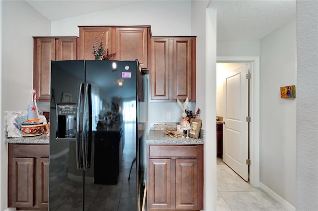 kitchen with light tile patterned floors, a textured ceiling, black refrigerator with ice dispenser, and vaulted ceiling