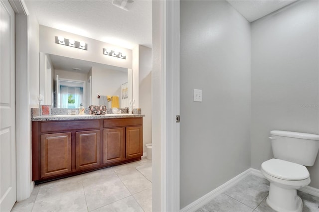 bathroom featuring tile patterned floors, vanity, a textured ceiling, and toilet