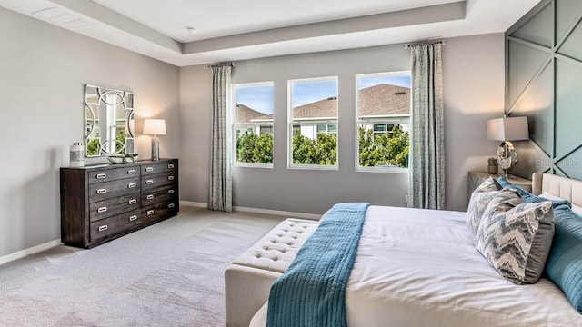 bedroom with light carpet and a raised ceiling