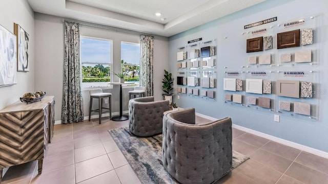 living area featuring a raised ceiling and light tile patterned floors