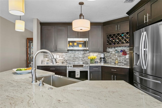 kitchen featuring backsplash, stainless steel appliances, light stone counters, and hanging light fixtures