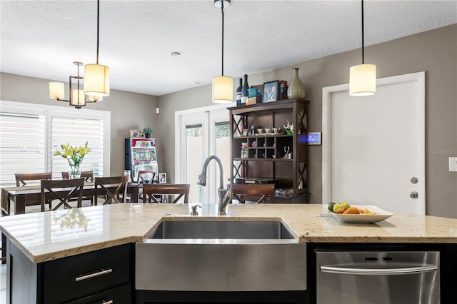 kitchen featuring plenty of natural light, an island with sink, pendant lighting, and a textured ceiling