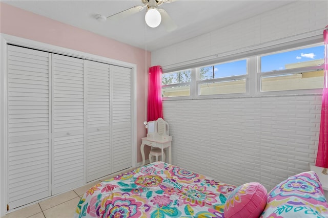 tiled bedroom featuring ceiling fan and a closet