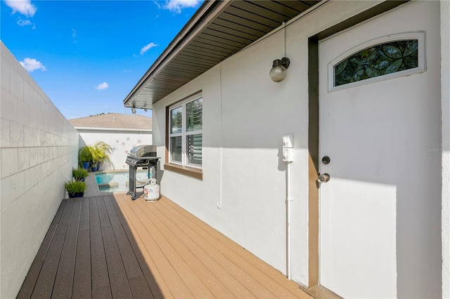 wooden terrace featuring area for grilling and a swimming pool