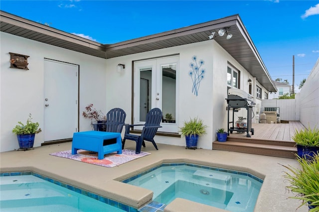 rear view of property with a patio area, a swimming pool with hot tub, and french doors