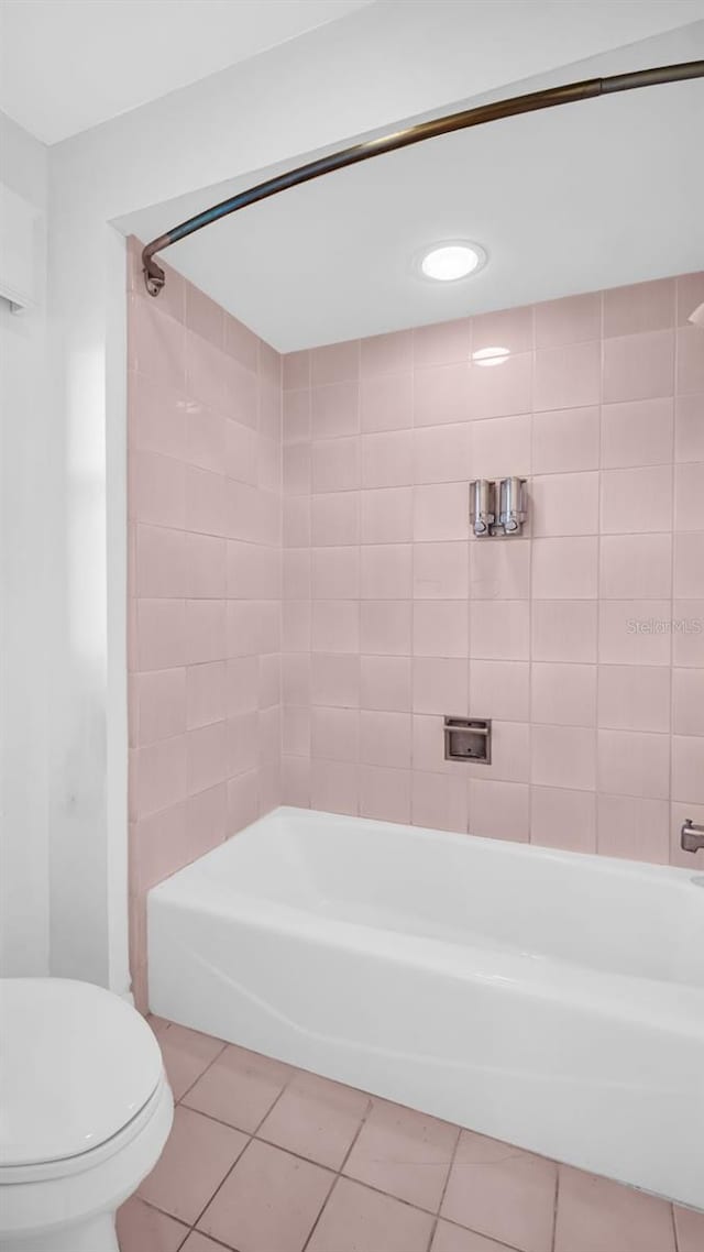 bathroom featuring tile patterned flooring, tiled shower / bath combo, and toilet