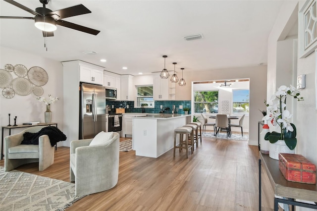 kitchen featuring white cabinets, stainless steel appliances, light hardwood / wood-style flooring, and a breakfast bar area