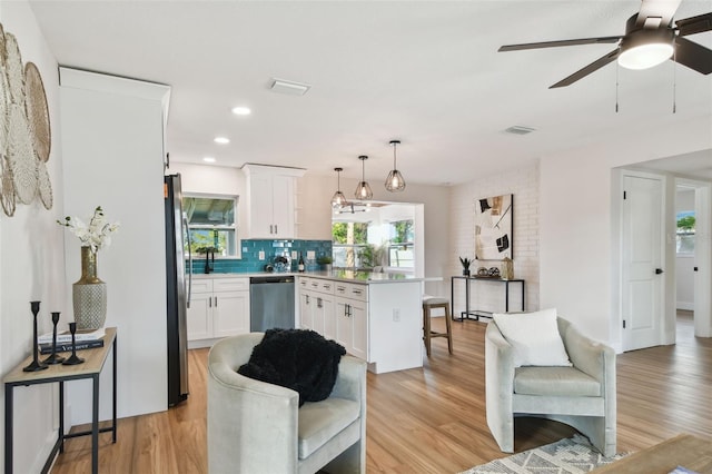 kitchen with white cabinets, decorative light fixtures, stainless steel appliances, and light hardwood / wood-style flooring