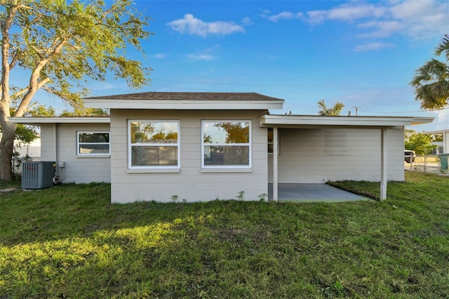 back of house with central AC unit, a patio area, and a lawn