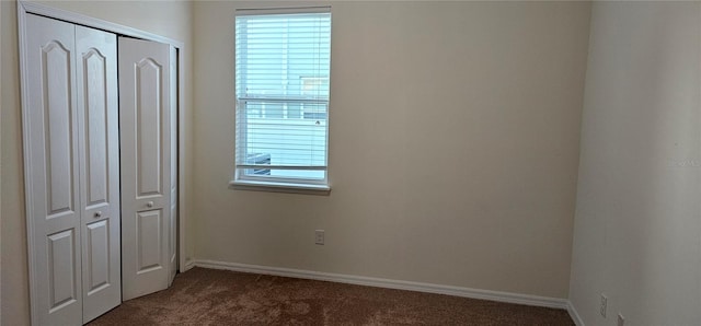 unfurnished bedroom featuring a closet and dark colored carpet