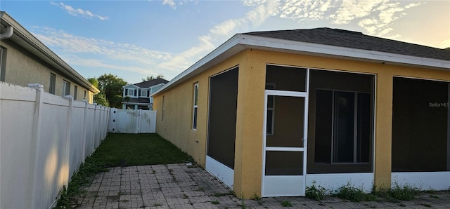 property exterior at dusk with a sunroom and a patio