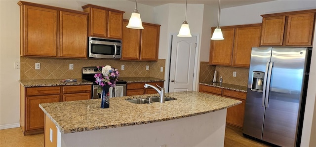 kitchen featuring sink, stainless steel appliances, tasteful backsplash, an island with sink, and pendant lighting