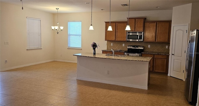 kitchen featuring a kitchen island with sink, hanging light fixtures, tasteful backsplash, stainless steel appliances, and a chandelier