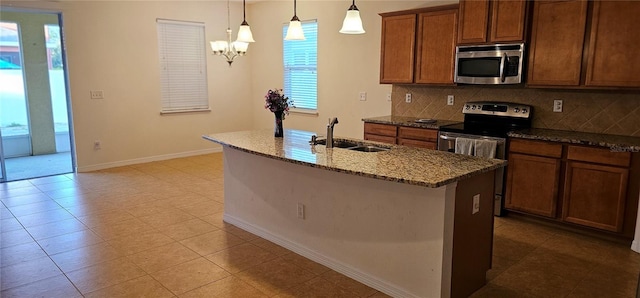 kitchen with sink, stainless steel appliances, backsplash, pendant lighting, and a center island with sink