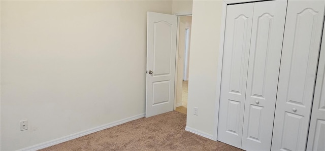 unfurnished bedroom with a closet and light colored carpet