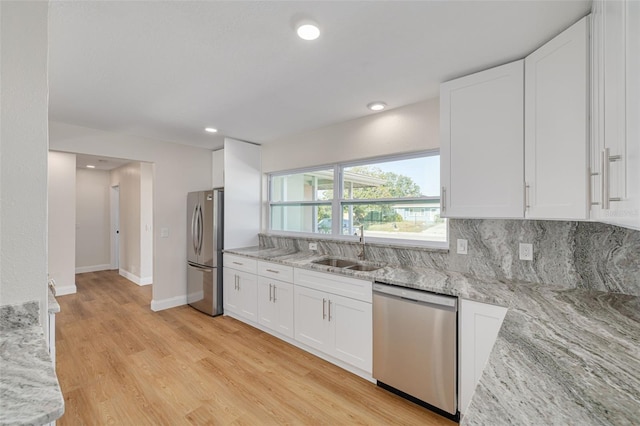 kitchen featuring white cabinetry, sink, light stone counters, light hardwood / wood-style flooring, and appliances with stainless steel finishes