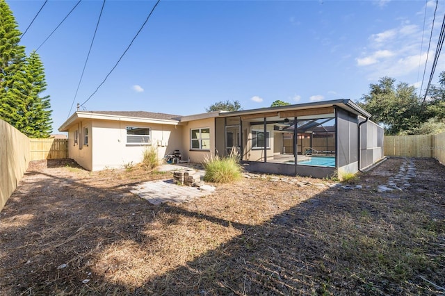 back of property with a fenced in pool, glass enclosure, and a patio