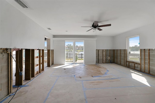 unfurnished room with ceiling fan, a water view, and a healthy amount of sunlight