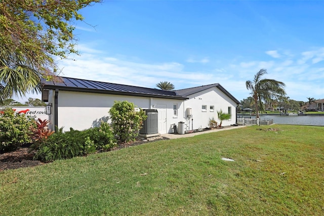 view of side of home with a lawn, cooling unit, and a water view