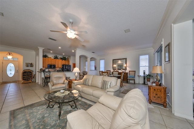 living room featuring light tile patterned floors, a textured ceiling, ceiling fan, and crown molding