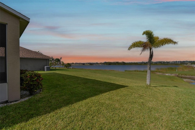 yard at dusk featuring a water view and central air condition unit