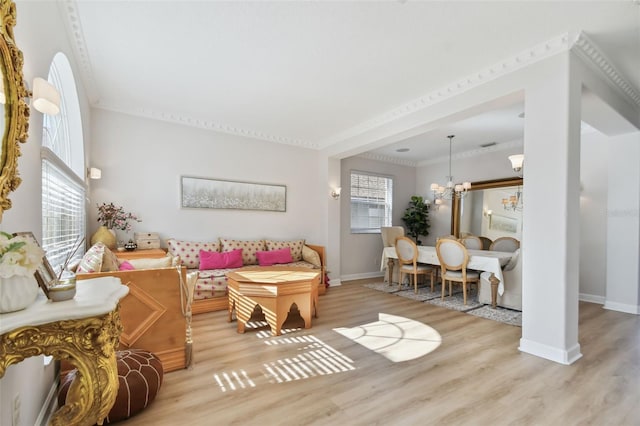 living room featuring a healthy amount of sunlight, ornamental molding, light hardwood / wood-style flooring, and a chandelier