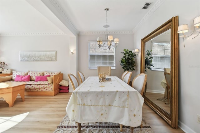 dining space with plenty of natural light, an inviting chandelier, ornamental molding, and light wood-type flooring